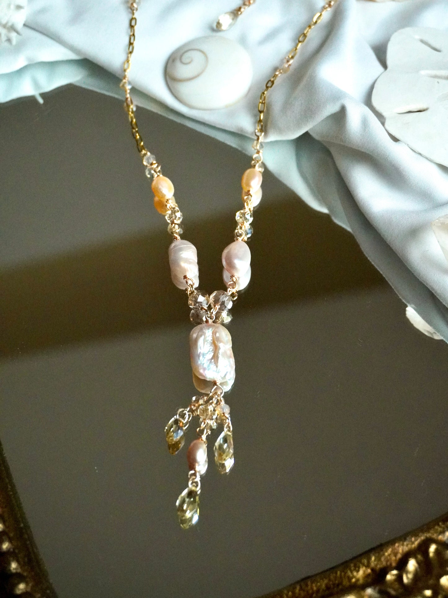 Pearl necklace with gold chain on a decorative surface