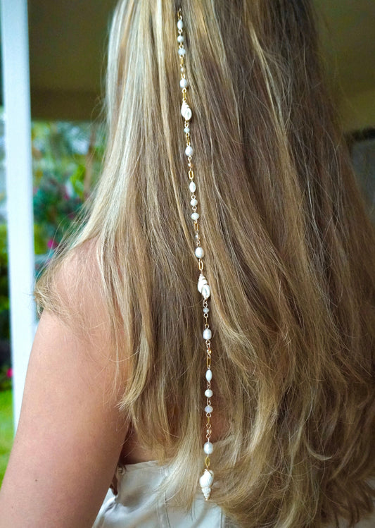 Long blonde hair with a decorative hair chain, blurred background